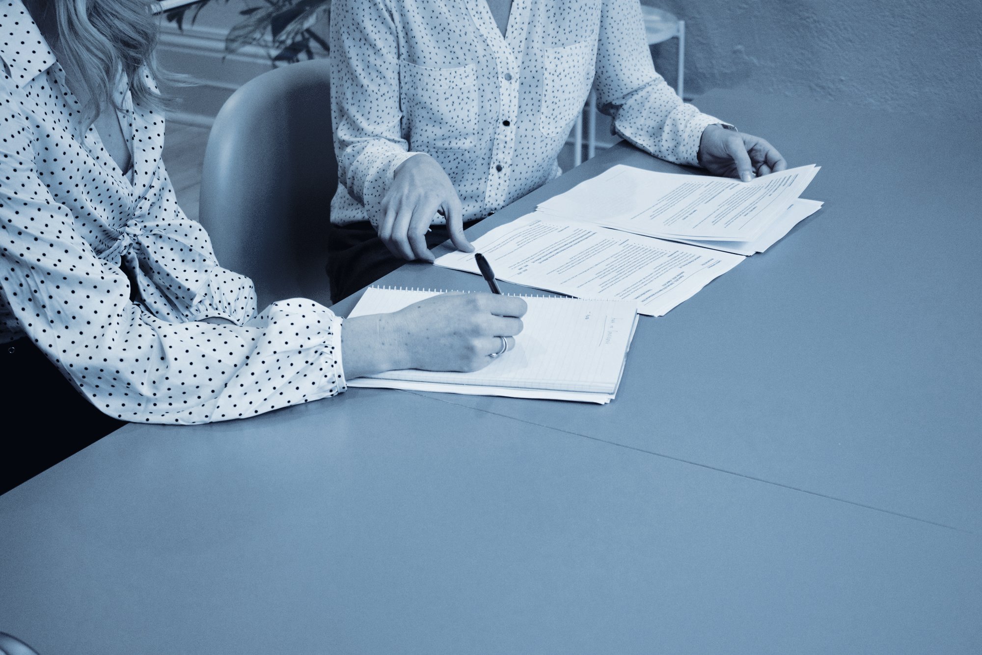 Two people reviewing and signing documents at a table